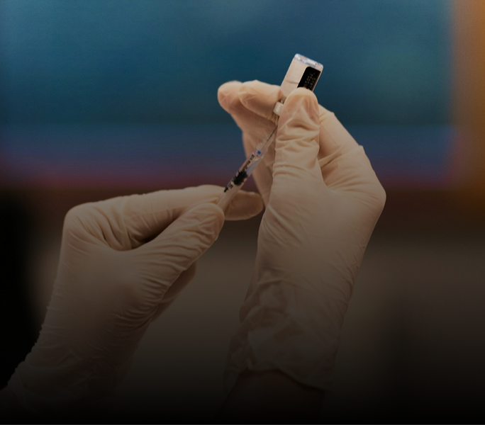 Gloved hands preparing a vaccine with syringe and vial